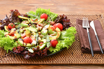 Plate with tasty avocado salad on table