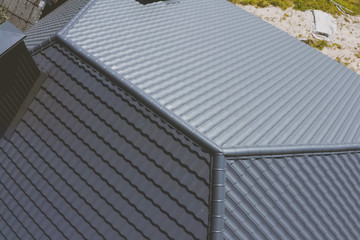 Gray-blue metal roof tiles on the roof of the house. Corrugated