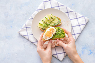 Woman eating tasty avocado sandwiches, top view