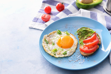 Plate with tasty avocado sandwich and fried egg on table