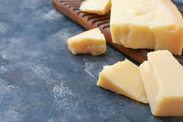 Board with tasty Parmesan cheese on grey background