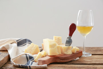 Board with tasty Parmesan cheese on wooden table