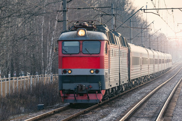 Passenger train approaches to the station at autumn morning time..