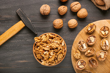 Tasty walnuts with hammer on wooden background