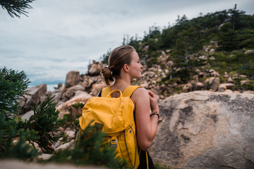 Young attractive girl wearing backpack and hiking in the rocky coastline in Australia