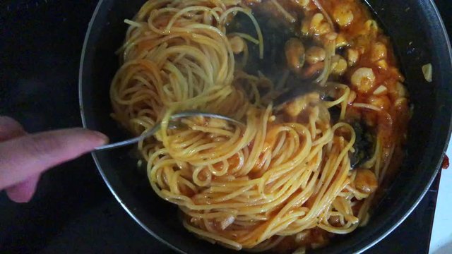 Chef cooking spaghetti seafood sauce. Prawns and mussels roasted on frying grill pan with garlic, parsley, white wine, cayenne, green sauce, lemon on in frying pan. Slow motion.