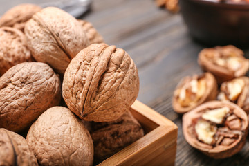 Box with tasty walnuts on wooden background, closeup