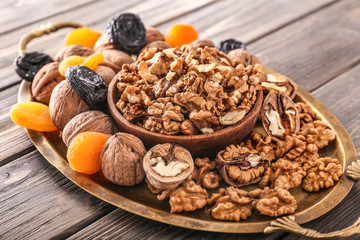 Tray with tasty walnuts and dried fruits on wooden background