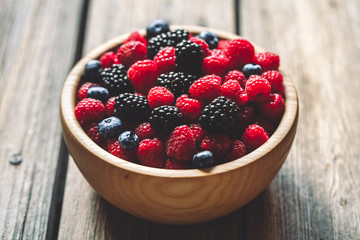 raspberries and blackberries on a wooden background in vintage style. Cutting board