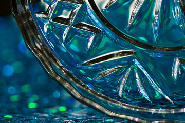 Macro abstract view of a crystal glass dish reflecting beautiful sparkling blue bokeh in the background