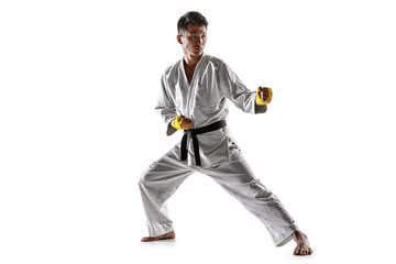 Confident korean man in kimono practicing hand-to-hand combat, martial arts. Young male fighter with black belt training isolated on white studio background. Concept of healthy lifestyle, sport.