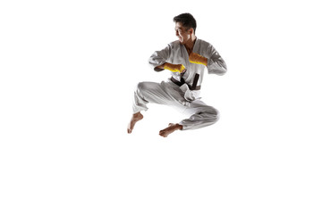 Confident korean man in kimono practicing hand-to-hand combat, martial arts. Young male fighter with black belt training isolated on white studio background. Concept of healthy lifestyle, sport.