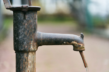 Old iron column. Water is pouring from a street column