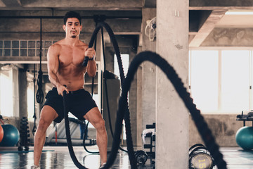 caucasian young man having workout in gym with rope © Mongkolchon