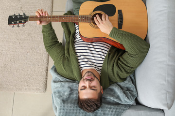 Handsome young man playing guitar at home