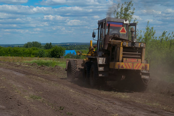 An old grader makes a rural road in the picturesque area of the Kursk region.