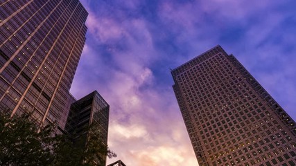 Day to night of a large office building with the lights coming on time lapse