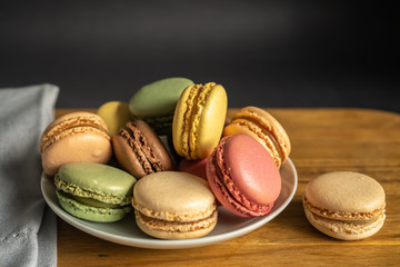 Colorful macarons on a white plate put on wood table. Colorful macarons french dessert
