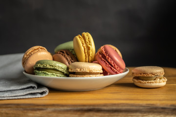 Colorful macarons on a white plate put on wood table. Colorful macarons french dessert