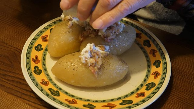 Two clips, handheld camera. Traditional Lithuanian cuisine meal - zeppelins or potato dumplings, cepelinai made from potato and minced meat and boiled.