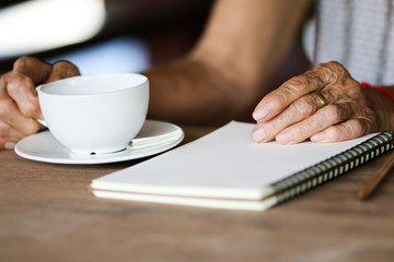 Old asian woman with white coffee cup on wooden table