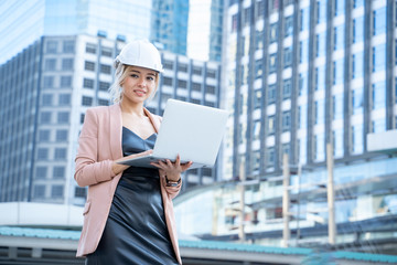Fototapeta premium Portrait of beautiful business Asia woman engineer developer holding laptop working Confident outdoors in construction site.