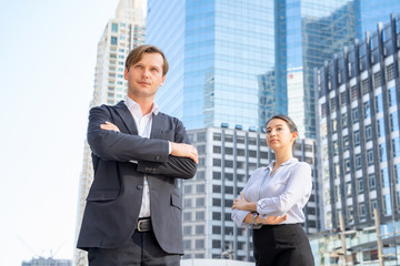 Businessman and businesswoman standing in street at the city and contact outdoor work about company projects,with city background,concept of work agility.