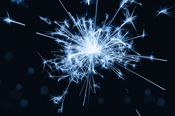 Burning blue sparkle with bokeh on black background. Christmas background