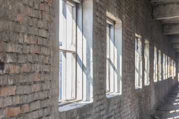 Old textured brick wall with several windows in an abandoned building