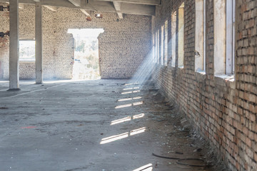 Interior of abandoned building with many windows. Visible rays of the sun hits the windows