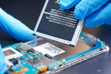 Asian Technician repairing micro circuit main board and battery of smartphone electronic technology...