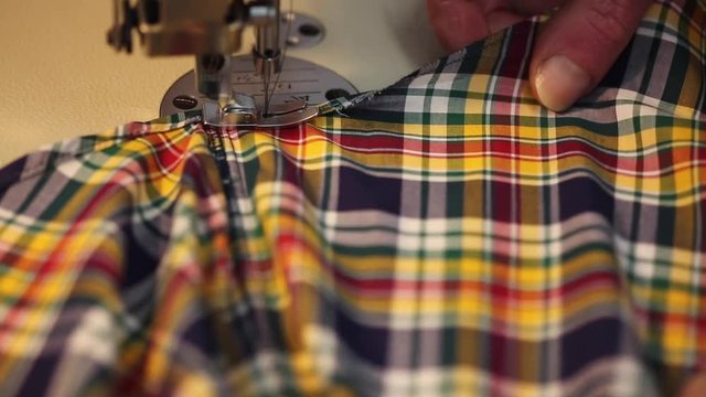 Close up of a male tailor sewing a shirt on an industrial sewing machine
