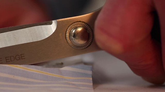 Extreme close up of a tailor cutting fabric/material along a pattern with scissors