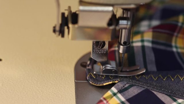 Extreme close up of a male tailor sewing a shirt on an industrial sewing machine