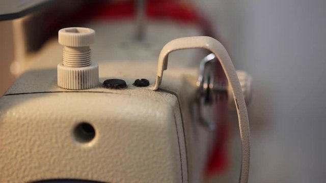 Extreme close up the arm of an industrial sewing machine in action stitching
