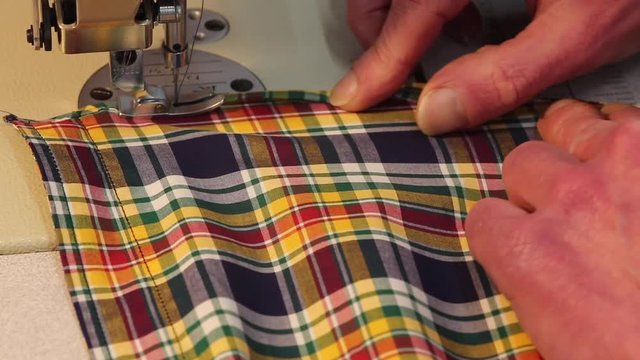 Close up of a male tailor sewing a shirt on an industrial sewing machine