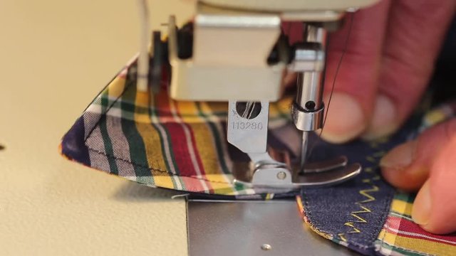 Close up of a tailor using a using an industrial  sewing machine to make a shirt
