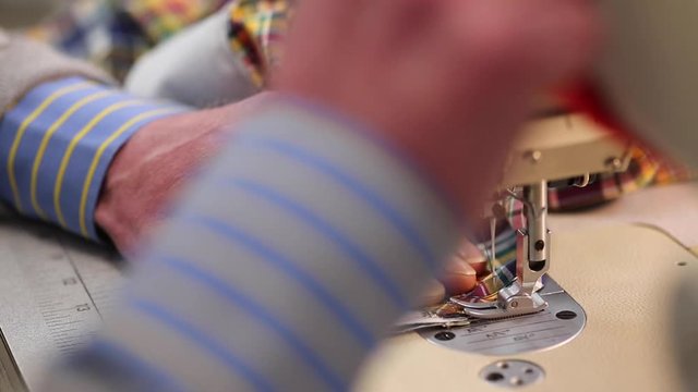 Close up of a male tailor sewing/stitching a shirt on an industrial sewing machine