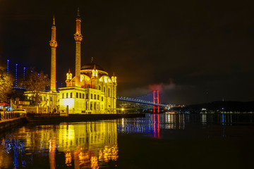 Obraz premium Istanbul, Turkey The Ortakoy Mosque under the Bosphorus Bridge, known officially as the 15 July Martyrs Bridge and unofficially as the First Bridge
