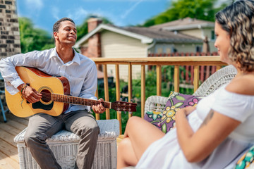 A mixed couple share their love of music; a young man playing guitar to his partner and unborn...