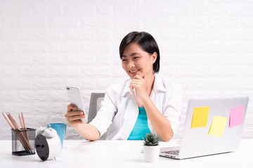 Woman sitting at home office and use smart phone taking a selfie