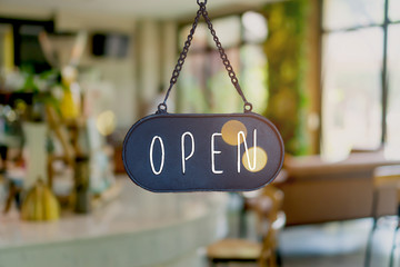 A business sign that says Open on cafe or restaurant hang on door at entrance. Vintage color tone style.