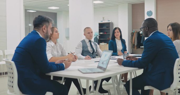 International group of businessmen discusses a company&rsquo;s business project, meeting. Colleagues are sitting at the table and discussing the project. Modern coworking center.