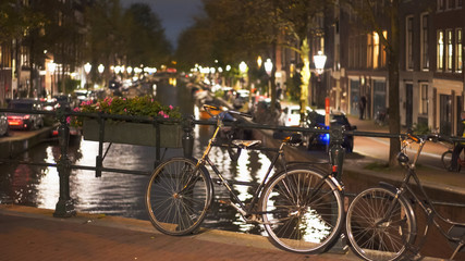 night shot of a bicycle on a bridge over a canal at amsterdam in the netherlands
