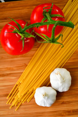 Ingredients used to make an Italian meal. Tomatos, bell peppers, garlic and spagetti 