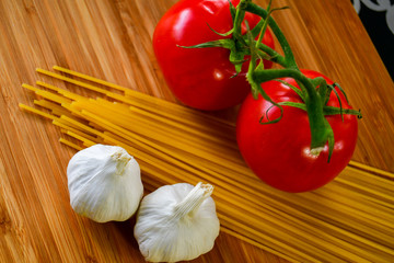 Ingredients used to make an Italian meal. Tomatos, bell peppers, garlic and spagetti 