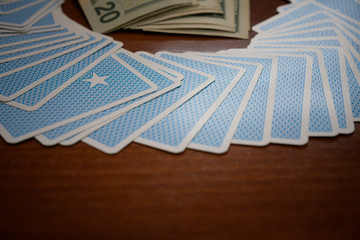 Blue cards gambler game with money on wooden table background.