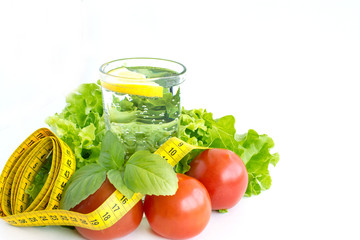 Clean water, salad, tape measure and cutlery on a white background. The concept of healthy eating and losing weight. Sports nutrition.