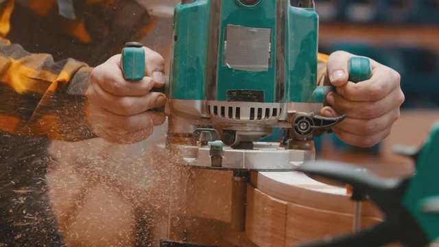 Carpentry indoors - a woodworker polishes a top of wooden plank