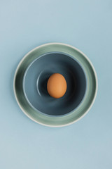 A green and a blue plate and an egg on blue background, top view, copy space